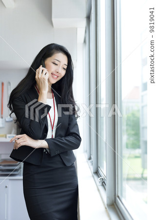 Young business woman using mobile phone outside office cubicle Young business woman using mobile phone outside office cubicle 9819041