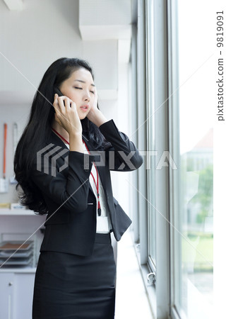 Young business woman using mobile phone outside office cubicle Young business woman using mobile phone outside office cubicle 9819091