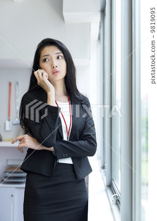 Young business woman using mobile phone outside office cubicle Young business woman using mobile phone outside office cubicle 9819095