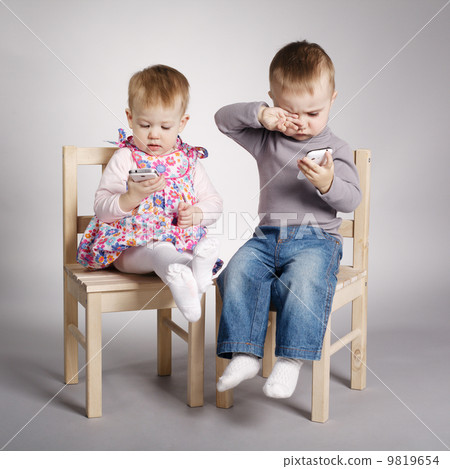 boy and girl playing with mobile phones boy and girl playing with mobile phones 9819654