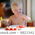 Funny happy healthy toddler sitting in high feeding chair eating cherry tomato 9821342