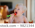 Funny happy healthy toddler sitting in high feeding chair eating cherry tomato 9821344