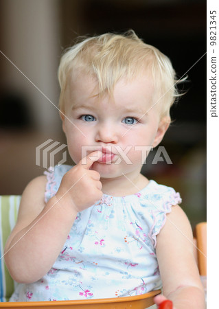 Funny happy healthy toddler sitting in high feeding chair biting on cherry tomato Funny happy healthy toddler sitting in high feeding chair biting on cherry tomato 9821345