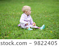Lovely baby girl in a beautiful kimono suit sitting on a grass in the middle of a park  9822405