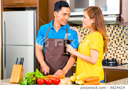 Asian couple preparing food in domestic kitchen 9824424