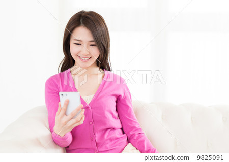 A woman watching a smartphone in a room 9825091