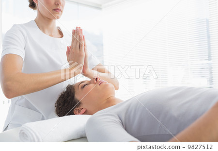 Therapist giving Reiki treatment to woman 9827512