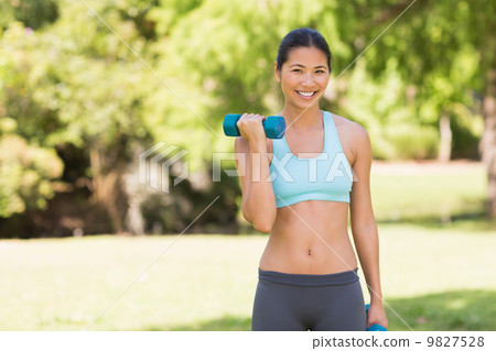 Healthy smiling woman exercising with dumbbells in park Healthy smiling woman exercising with dumbbells in park 9827528