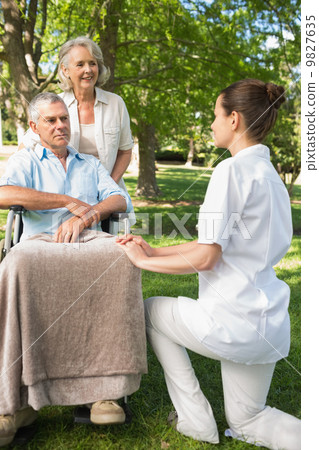 Women with mature man sitting in wheel chair at park Women with mature man sitting in wheel chair at park 9827635