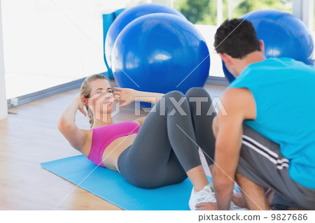 Trainer helping woman with her exercises at gym 9827686