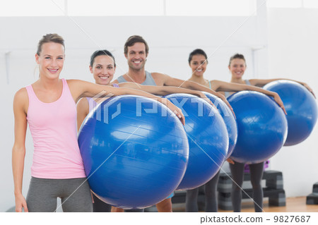 Fitness class holding exercise balls at fitness studio 9827687