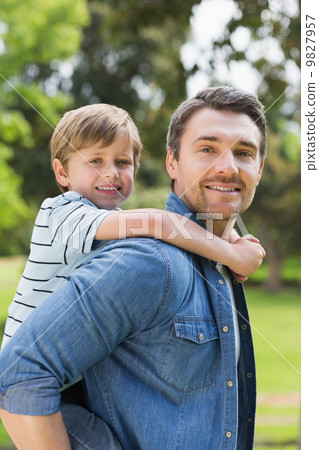 Portrait of father carrying boy on back at park Portrait of father carrying boy on back at park 9827957