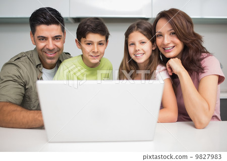 Portrait of a smiling couple with kids using laptop 9827983