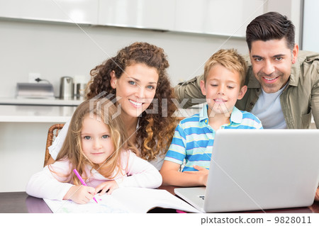 Happy parents colouring and using laptop with their children 9828011
