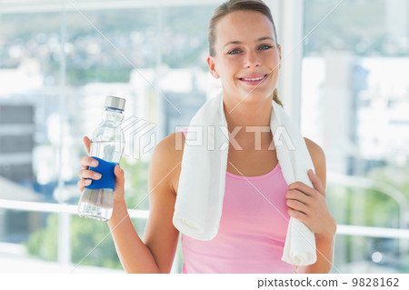 Woman with towel and water bottle in gym