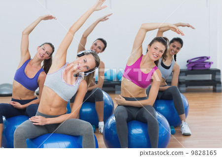 Sporty women stretching hands on exercise balls at gym 9828165