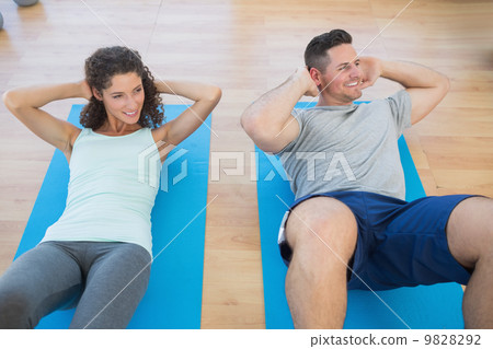 Couple doing sit ups at gym Couple doing sit ups at gym 9828292