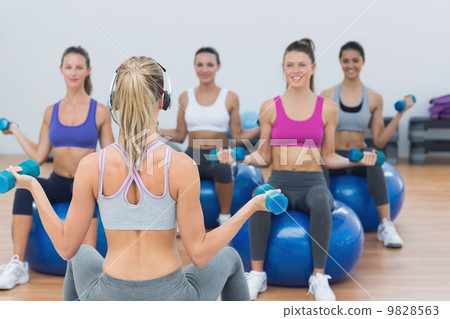 Fit class exercising with dumbbells on fitness balls Fit class exercising with dumbbells on fitness balls 9828563