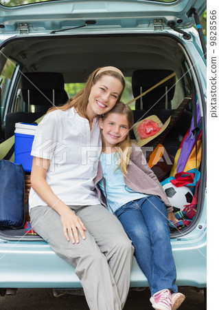 Smiling mother and daughter sitting in car trunk Smiling mother and daughter sitting in car trunk 9828566