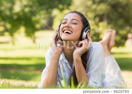 Cheerful young woman enjoying music in park Cheerful young woman enjoying music in park 9828793