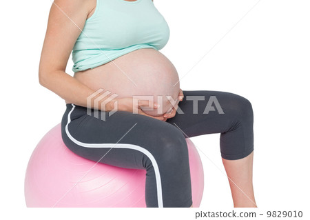 Pregnant woman sitting on pink exercise ball 9829010