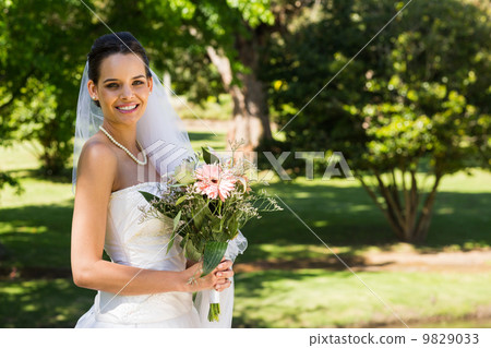 Smiling young beautiful bride with bouquet in park Smiling young beautiful bride with bouquet in park 9829033