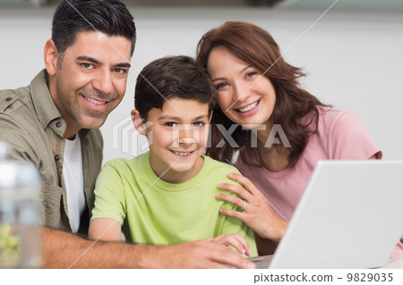 Smiling couple with son using laptop Smiling couple with son using laptop 9829035