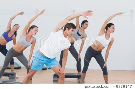 Class doing stretching exercise in fitness studio 9829147