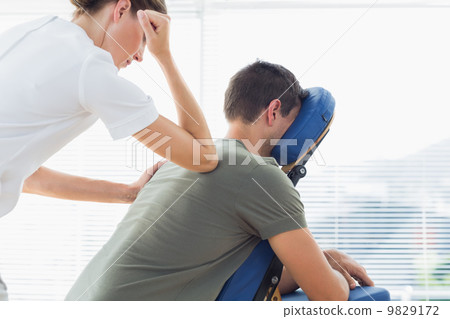 Therapist giving back massage to man 9829172