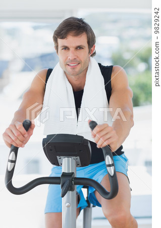 Smiling man working out at spinning class in bright gym 9829242