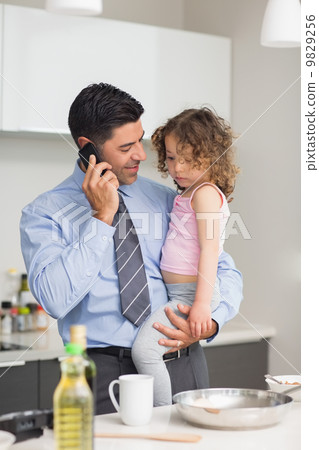 Well dressed father with daughter preparing food while on call Well dressed father with daughter preparing food while on call 9829256