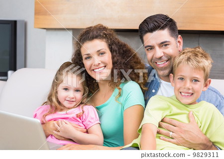 Cheerful family sitting on sofa with laptop Cheerful family sitting on sofa with laptop 9829311