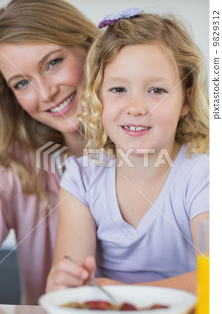 Girl having breakfast while sitting with mother Girl having breakfast while sitting with mother 9829312