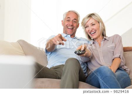 Cheerful couple watching tv at home Cheerful couple watching tv at home 9829416