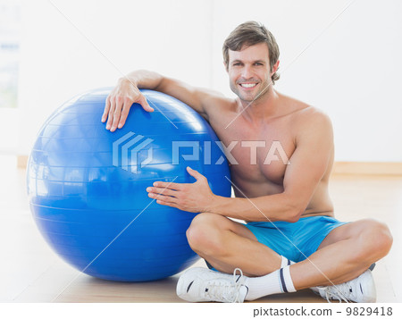 Shirtless man with fitness ball in gym 9829418