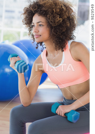 Young woman exercising with dumbbells in gym Young woman exercising with dumbbells in gym 9829549