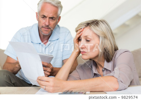 Concentrated mature couple with bills at home 9829574