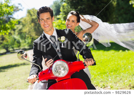 Newlywed couple enjoying scooter ride 9829626