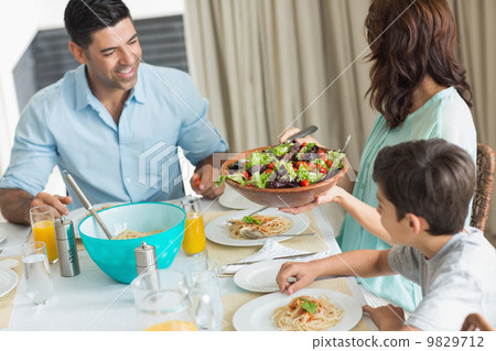 Happy family of three sitting at dining table 9829712