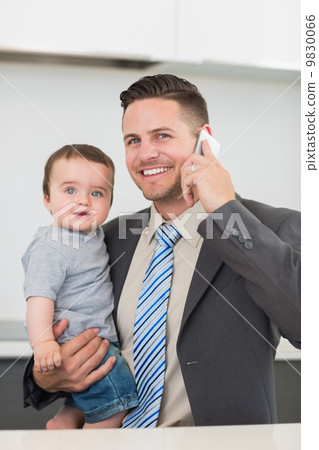 Businessman carrying baby boy while on call 9830066