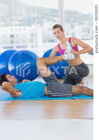 Female trainer helping man with his exercises at gym Female trainer helping man with his exercises at gym 9830085