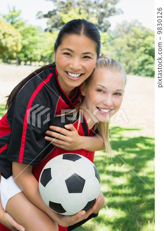 Female soccer player piggybacking teammate 9830126