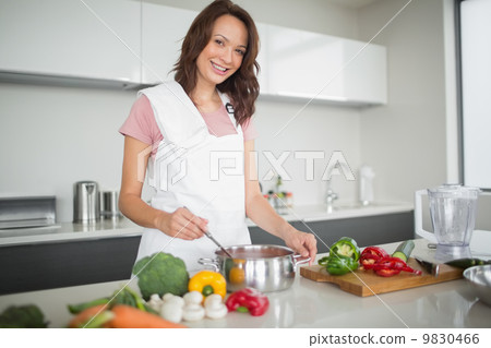 Portrait of smiling woman preparing food in kitchen 9830466