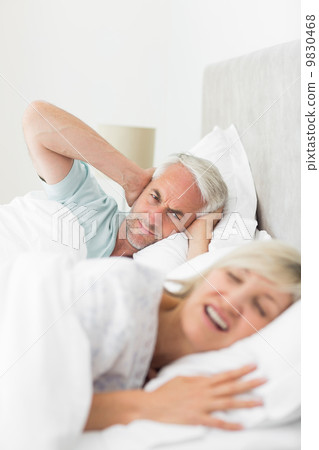 Man covering ears while woman shouting in bed 9830468