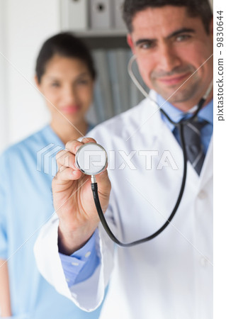 Confident doctor holding stethoscope Confident doctor holding stethoscope 9830644