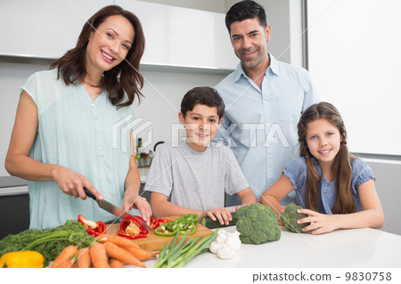 Family chopping vegetables in kitchen 9830758