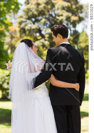 Rear view of newlywed with arms around in park Rear view of newlywed with arms around in park 9831029