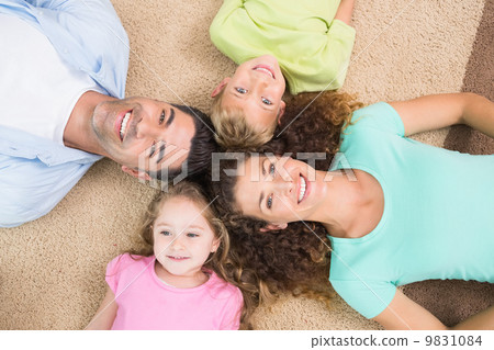 Happy family lying on the rug in a circle 9831084