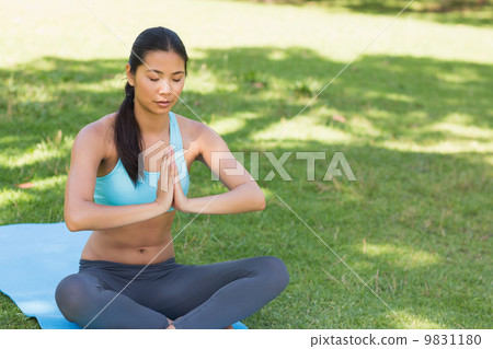 Woman in Namaste position with eyes closed at park Woman in Namaste position with eyes closed at park 9831180