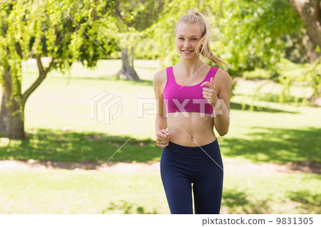 Healthy and beautiful woman in sports bra jogging in park 9831305